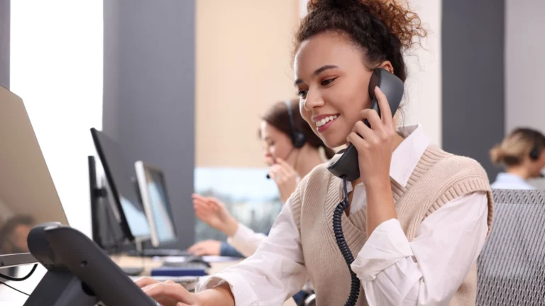 Femme-d'affaires- est-assise-à-son-bureau-parlant-au-téléphone
